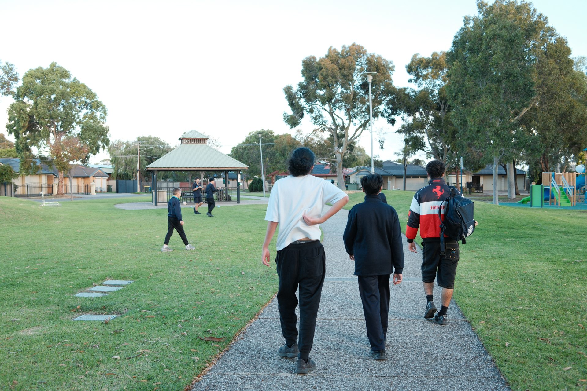 Three young people walking together along a path through the park